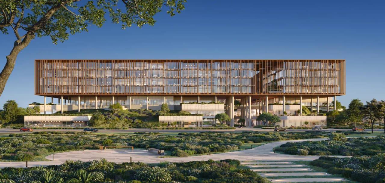 Front elevation of The Yards Plaza: a long copper-finned office facade raised above a landscaped ground plane